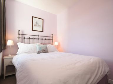 A bedroom with a white bed and two bedside tables with lamps at Inveray in Seahouses