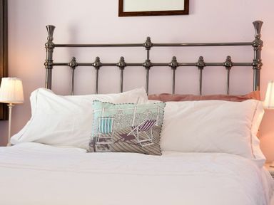 A bed with a metal headboard with pillows and a decorative cushion in a bedroom