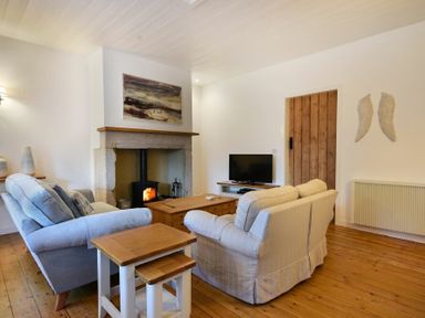 A living room with sofas a fireplace a television and wooden furniture at Periwinkle in Bamburgh