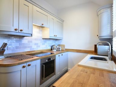 A kitchen with cabinets a stove an oven a sink a toaster a kettle and knives at Periwinkle in Bamburgh