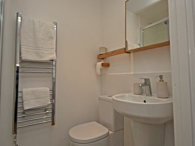 A small bathroom with a toilet sink mirror towel rack and toilet paper holder at Periwinkle in Bamburgh