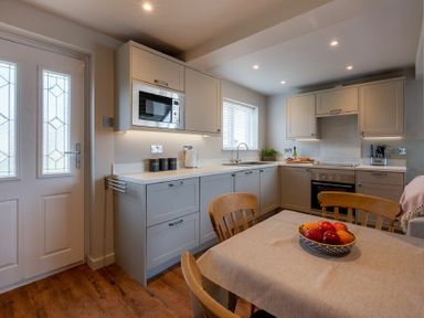 A kitchen with wooden chairs a table with fruit and cabinets at Castle View Bamburgh