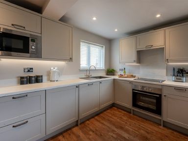 A kitchen with grey cabinets a microwave oven and cooking utensils at Castle View Bamburgh