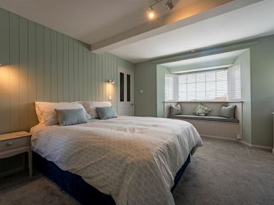 A bedroom with a large bed beside a window seat with cushions at Castle View Bamburgh