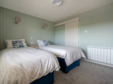 A bedroom with two single beds with white bedding and blue cushions at Castle View Bamburgh