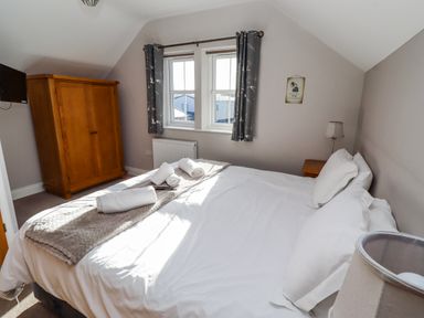 A bedroom with a bed, wardrobe, and windows at Bramley in Lucker