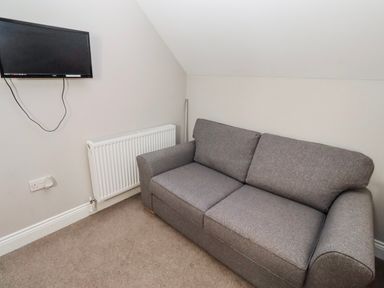 A living room with a sofa and a television at Bramley in Lucker
