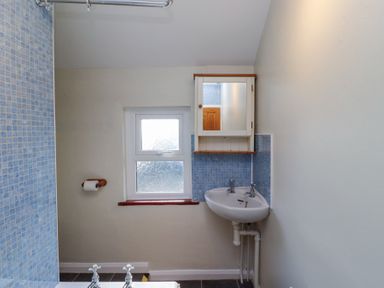 A bathroom with a corner sink and mirror cabinet above it and a frosted window at St Marys Cottages No1 Low Newton-by-the-Sea