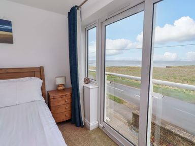 A bedroom with a bed and a window view at Farne Cottage in Beadnell
