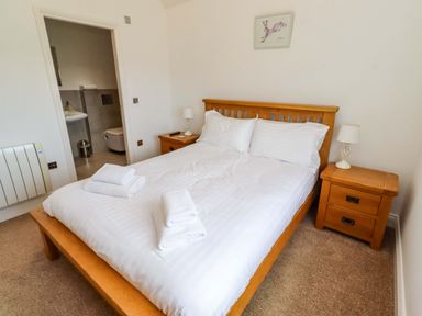 A bedroom with a bed and nightstands at Farne Cottage Beadnell