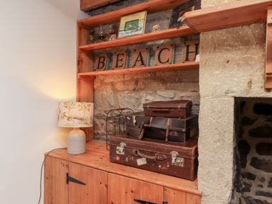 A wooden shelf with vintage suitcases and a lamp next to a stone wall at Hares Form in Seahouses