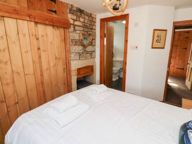 A bedroom with a bed and folded towels an open door leading to a bathroom at Hares Form in Seahouses