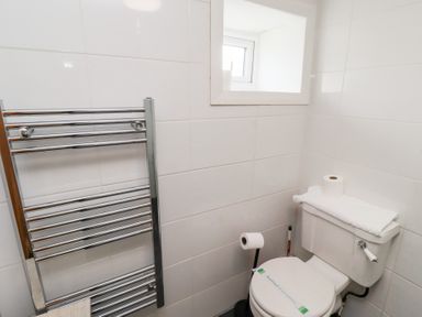 A bathroom with a toilet paper holder radiator and a small window at Hares Form in Seahouses