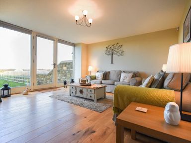 A living room with two sofas a coffee table and large glass doors at The Pepper Pot in Warkworth