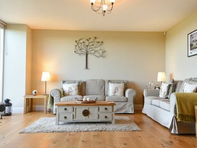 A living room with two sofas a coffee table two side tables with lamps and wall art at The Pepper Pot in Warkworth