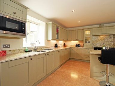 A kitchen with beige cabinets microwave oven sink and bar stool at The Pepper Pot in Warkworth