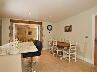 A kitchen with a marble countertop and black chairs next to a wooden dining table with white chairs at The Pepper Pot in Warkworth