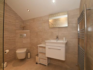 A bathroom with a wall-mounted toilet sink with a mirror above and a towel radiator at The Pepper Pot in Warkworth