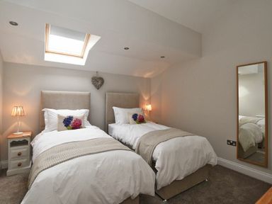 A bedroom with two single beds bedside tables with lamps a wall mirror and a skylight at The Pepper Pot in Warkworth