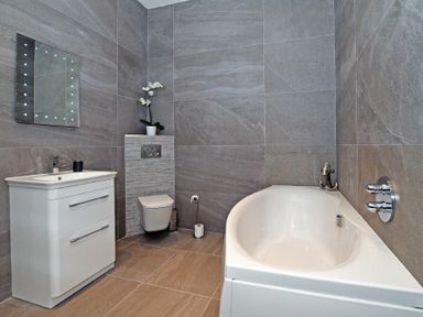 A bathroom with a bathtub toilet sink and mirror at The Pepper Pot in Warkworth