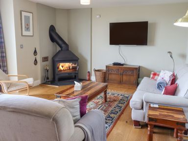 A living room with a wood stove television sofas and a wooden coffee table at The Mustard Pot in Acklington