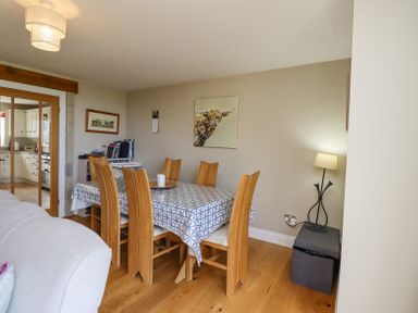 A dining room with a wooden table and six chairs a lamp and wall art at The Mustard Pot in Acklington