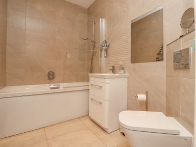 A bathroom with a bathtub shower combination a sink cabinet a wall mirror and a toilet at The Mustard Pot in Acklington