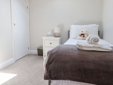 A bedroom with a single bed a teddy bear on the bed and folded towels on a blanket at The Mustard Pot in Acklington