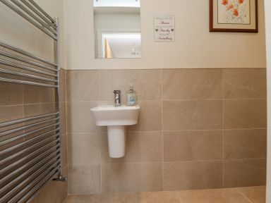 A bathroom sink with a soap dispenser a mirror towel radiator and wall art at The Mustard Pot in Acklington