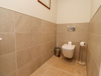 A toilet with a wall-mounted flush and two toilet paper holders in a tiled bathroom at The Mustard Pot in Acklington