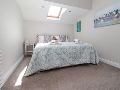 A bedroom with a bed covered with a patterned bedspread and towels on top a nightstand with tissues and framed artwork on the walls at The Mustard Pot in Acklington