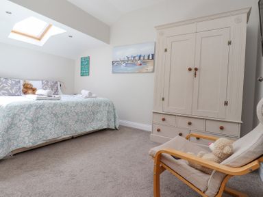 A bedroom with a double bed topped with towels and pillows a wardrobe and a wooden armchair with a teddy bear at The Mustard Pot in Acklington