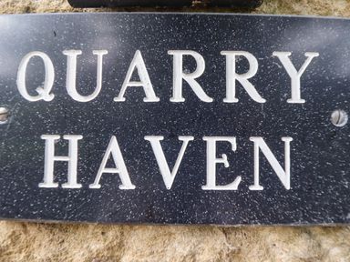 A close up of a black sign with white lettering that reads Quarry Haven