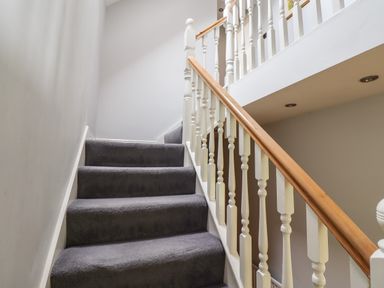 A carpeted staircase with white wooden balusters and a wooden handrail