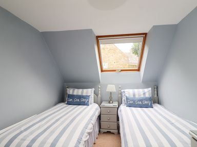 A bedroom with two single beds separated by a small nightstand under a skylight window at Quarry Haven in Bamburgh