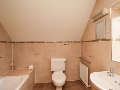A bathroom with a toilet sink bathtub and towel rail at Quarry Haven in Bamburgh
