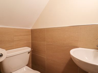 A bathroom with a toilet and a sink with tiled walls at Quarry Haven in Bamburgh