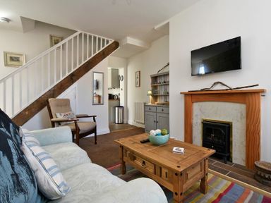 A living room with a sofa armchair wooden coffee table fireplace and stairs at Sea Air in Amble