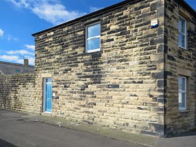Exterior view of a stone house with a blue door and three windows at Sea Air in Amble