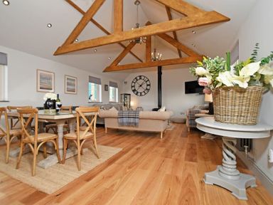 A living area with wooden dining table and chairs beige sofas wooden ceiling beams at The Hemmel Beadnell