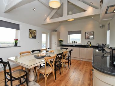 A kitchen with a dining table and chairs under exposed beams at The Hemmel (Beadnell) in Beadnell