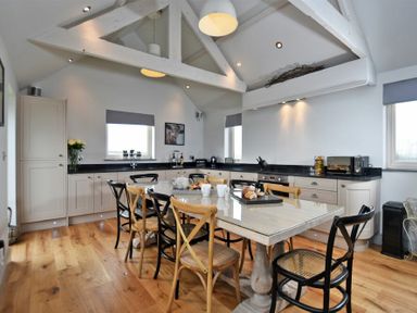 A kitchen with a dining table and chairs under exposed wooden beams at The Hemmel (Beadnell) in Beadnell