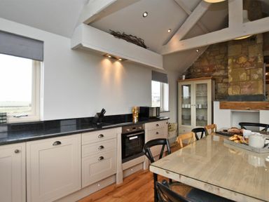 A kitchen with countertop oven cabinets dining table and chairs at The Hemmel (Beadnell) in Beadnell