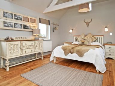 A bedroom with a bed a rug a dresser a window and wall decorations at The Hemmel Beadnell