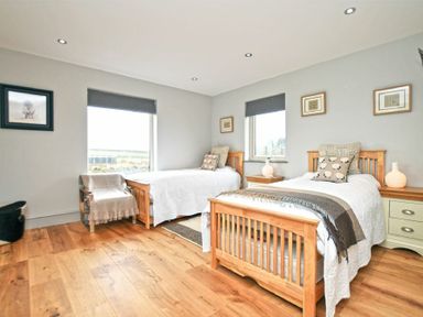 A bedroom with two wooden single beds white bedding pillows framed pictures and wooden floor at The Hemmel Beadnell