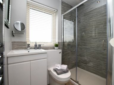 A bathroom with a sink cabinet toilet with towels and a glass shower at The Hemmel Beadnell