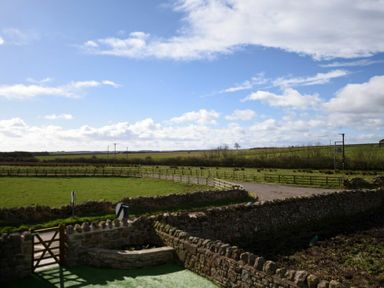 A rural landscape with stone walls and fenced grassy fields at The Hemmel Beadnell