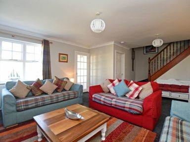 A living room with two sofas a wooden coffee table and a staircase at Armstrong Cottages No22 Bamburgh