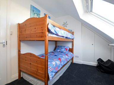 A bedroom with wooden bunk beds and geometric patterned bedding at Armstrong Cottages No22 in Bamburgh