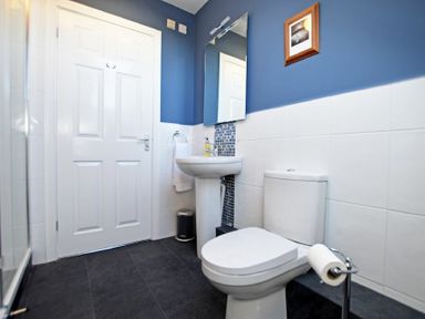A bathroom with a white toilet pedestal sink mirror and towel ring at Armstrong Cottages No22 in Bamburgh